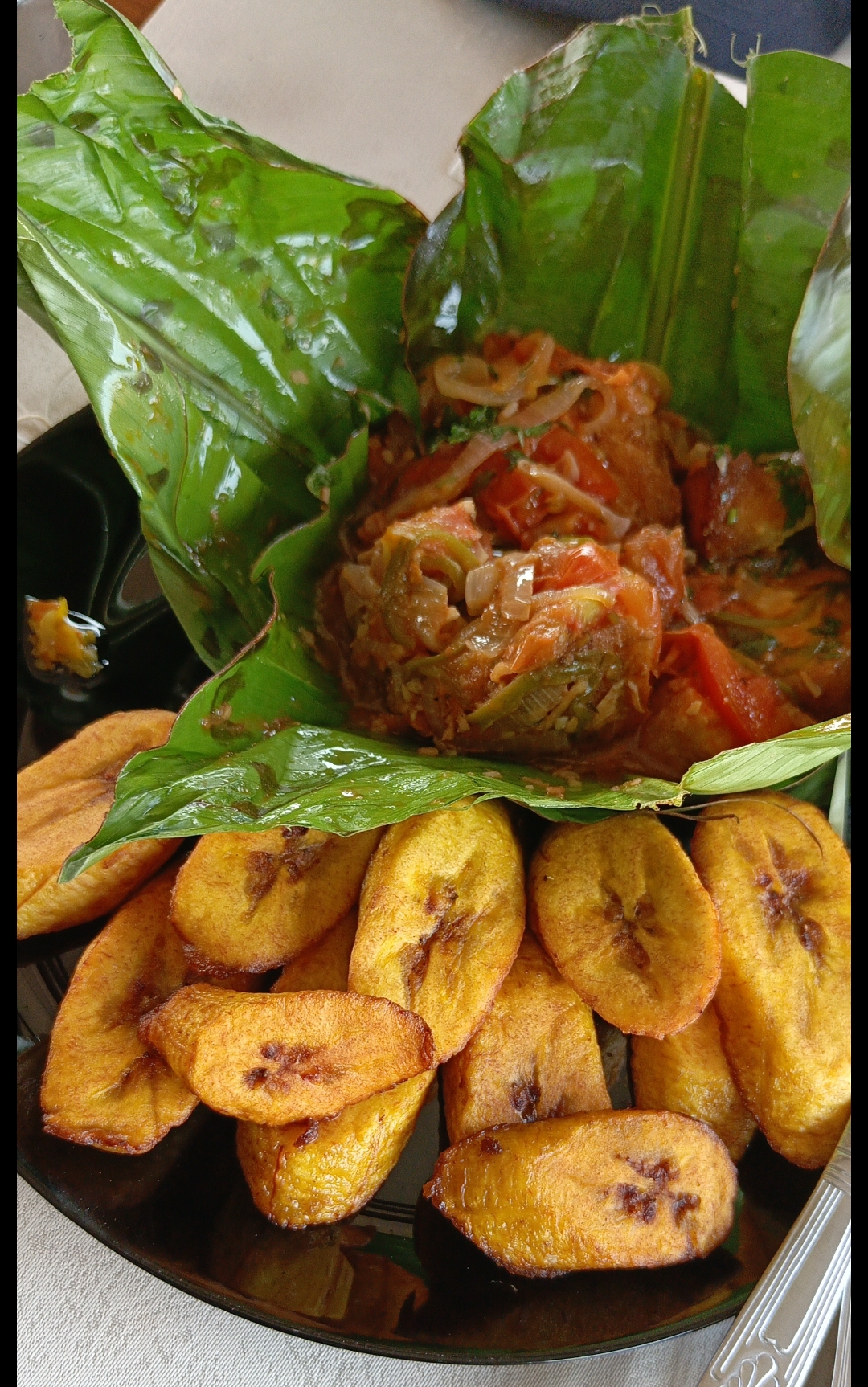 Liboké de poisson — fish and tomato stew steamed inside a banana leaf, served with fried plantain, a traditional Congolese dish